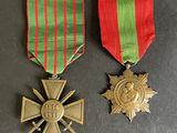 two medals and a cross on a table with a red and green ribbon