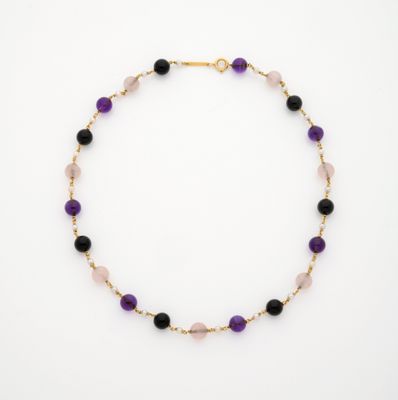 un collier composé de perles violettes et noires, monté sur une chaîne plaquée or