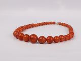 a close up of a red beaded necklace on a white background