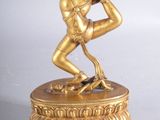 figurine en laiton représentant un homme en train de danser, posée sur un socle