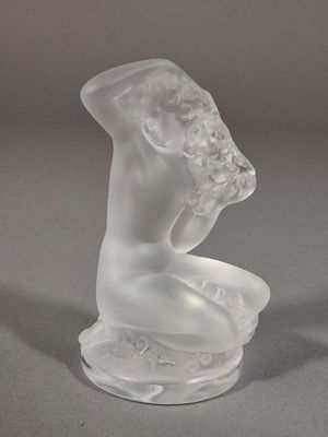 une sculpture en verre représentant une femme assise sur une table