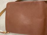 leather handbag with a brown leather strap on a white surface