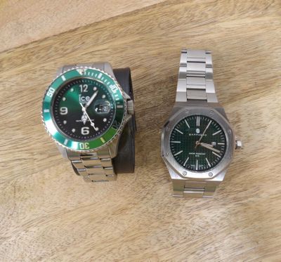 two watches sitting on a wooden table next to each other