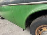 a green truck with a flat tire parked on the side of the road