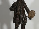 une statue en bronze représentant un homme tenant un éventail et une lampe