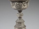 an antique silver cup with a design on the top of it