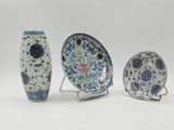 three pieces of chinese pottery on stands on a white surface