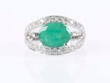 a close up of a ring with a green stone surrounded by diamonds