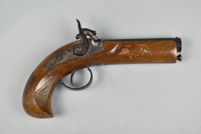 un vieux pistolet avec une poignée en bois sur une surface blanche