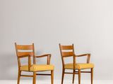 two wooden chairs with yellow upholstered seats against a gray wall
