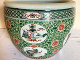 a green vase with a dragon design on it on a table
