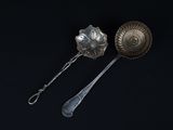 two silver spoons and a silver spoon on a black surface