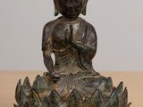 statue d'un Bouddha assis sur une fleur de lotus posée sur une table en bois