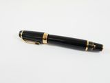 un stylo noir et or posé sur une surface blanche