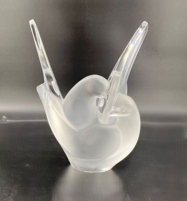 a clear glass bird sitting on top of a table next to a black table