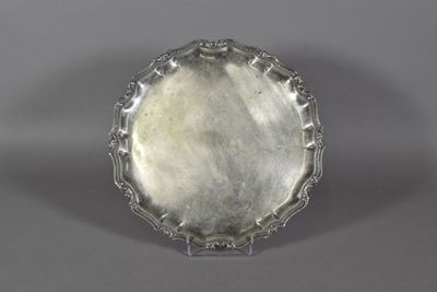 a silver plate on a stand on a gray surface