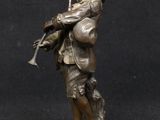 bronze figurine of a boy with a gun and a hat