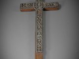 une croix en bois ornée de sculptures sur fond gris