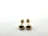 une paire de boucles d'oreilles noires et dorées posées sur une surface blanche