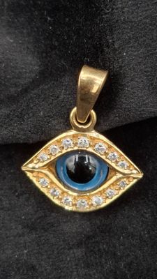 un gros plan sur un pendentif en or orné d'un œil bleu