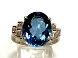 an image of a ring with a blue topaz stone surrounded by diamonds