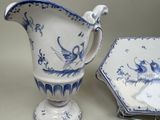a blue and white pitcher and a plate on a table