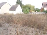 deux maisons à l'arrière-plan et un champ envahi par les mauvaises herbes au premier plan