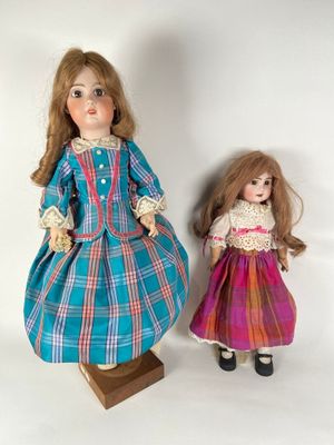 two dolls are standing next to each other on a white surface