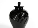 un vase noir posé sur une surface blanche