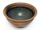 a brown bowl that is sitting on a white surface