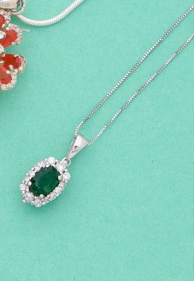 un gros plan d'un collier orné d'une pierre verte entourée de fleurs blanches et rouges