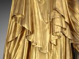 statue of a woman in a gold dress holding a cane