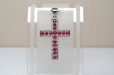 un gros plan d'une croix composée de pierres rouges dans une boîte transparente