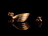 deux bagues en or et une paire de boucles d'oreilles posées sur une surface noire