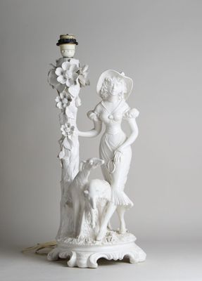une statue blanche représentant une femme et un chien, posée sur un socle