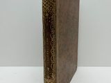 un livre en cuir marron, avec des bordures dorées et un motif décoratif sur la couverture