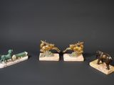 three figurines of horses and a dog on a wooden base