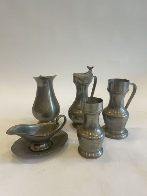 three silver vases and a saucer on a white surface