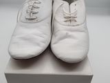 pair of white shoes sitting on top of a box on a white surface