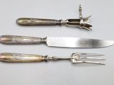 three knives and a fork on a white table