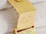 a close up of a gold watch on a white glove