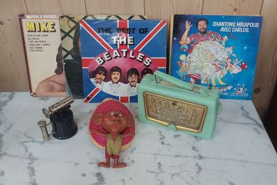 une table sur laquelle se trouvent divers objets, notamment une radio, un tourne-disque et d'autres objets