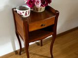 a small wooden table with a bowl of flowers on it