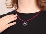 the woman is wearing a black shirt and a red beaded necklace