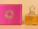 a close up of a bottle of perfume next to a pink box