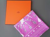 le foulard Hermès et son coffret sont posés sur une surface grise
