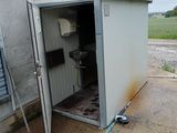 des toilettes situées dans l'embrasure de la porte d'un petit bâtiment