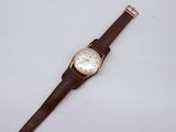 a close up of a watch on a white surface with a brown strap