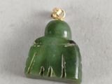 a close up of a green jade pendant with a gold plated clasp