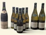 several bottles of wine sitting next to each other on a white surface